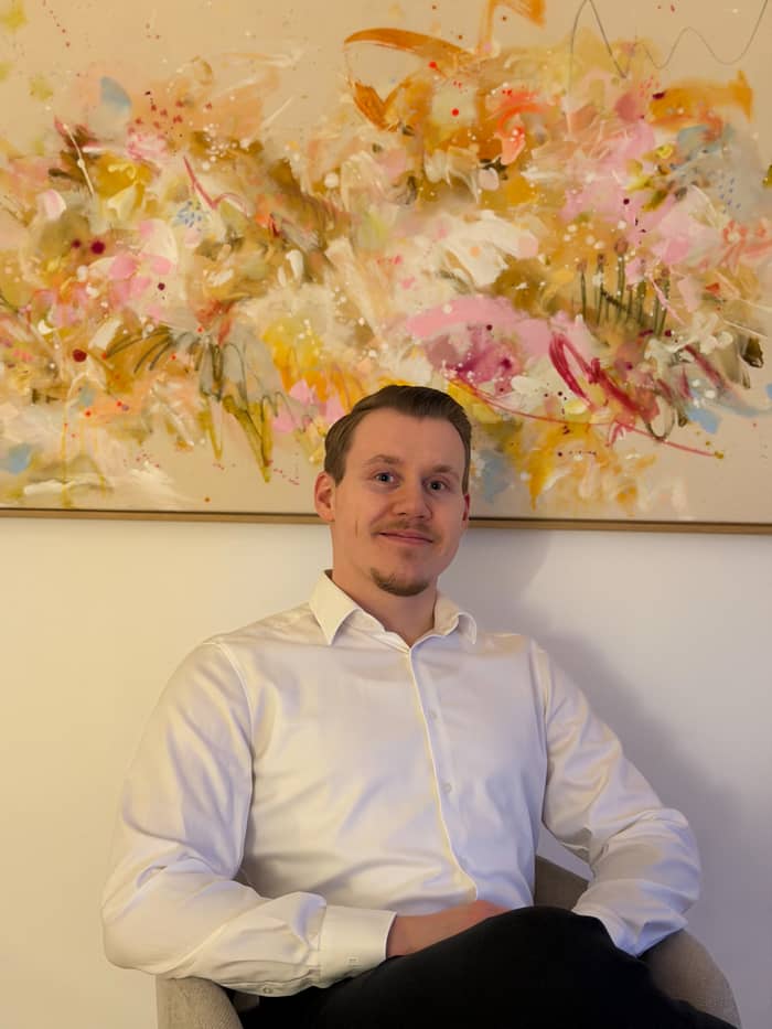 Psychotherapeut Michael Odenthal sitzend vor einem bunten Bild an der Wand