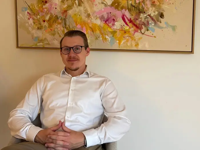 dr-michael-odenthal-ueber-mich Michael Odenthal vor einer Wand mit Holzpaneelen